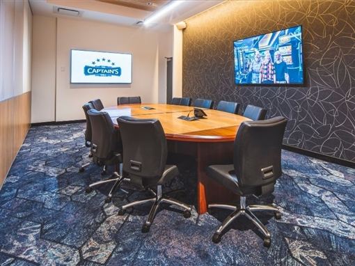The Captain's Table board room, with a long table and two TV screens